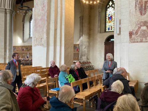 people sit inside an old church looking at ancient wall paintings